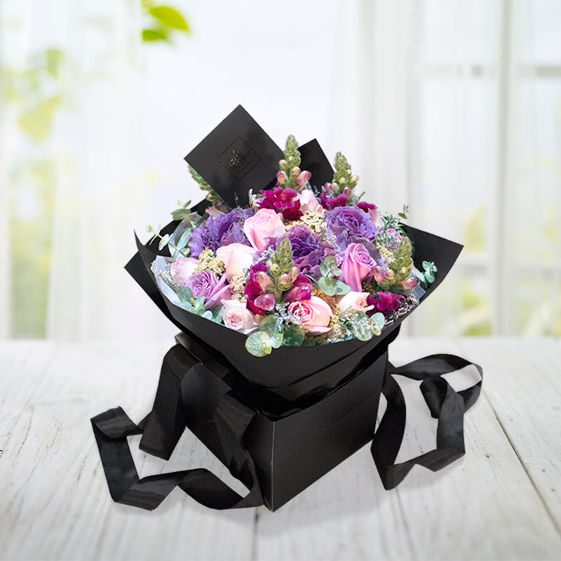 Bouquet Rosas lilas y rosadas con Eucalipto, Limonio, Aquilea y Lechuga con follajes de flores varias, atado a mano y envuelto en delicados y elegantes capas de papel. El arreglo incluye tarjeta personalizada, moño de tela y alimento para flores.