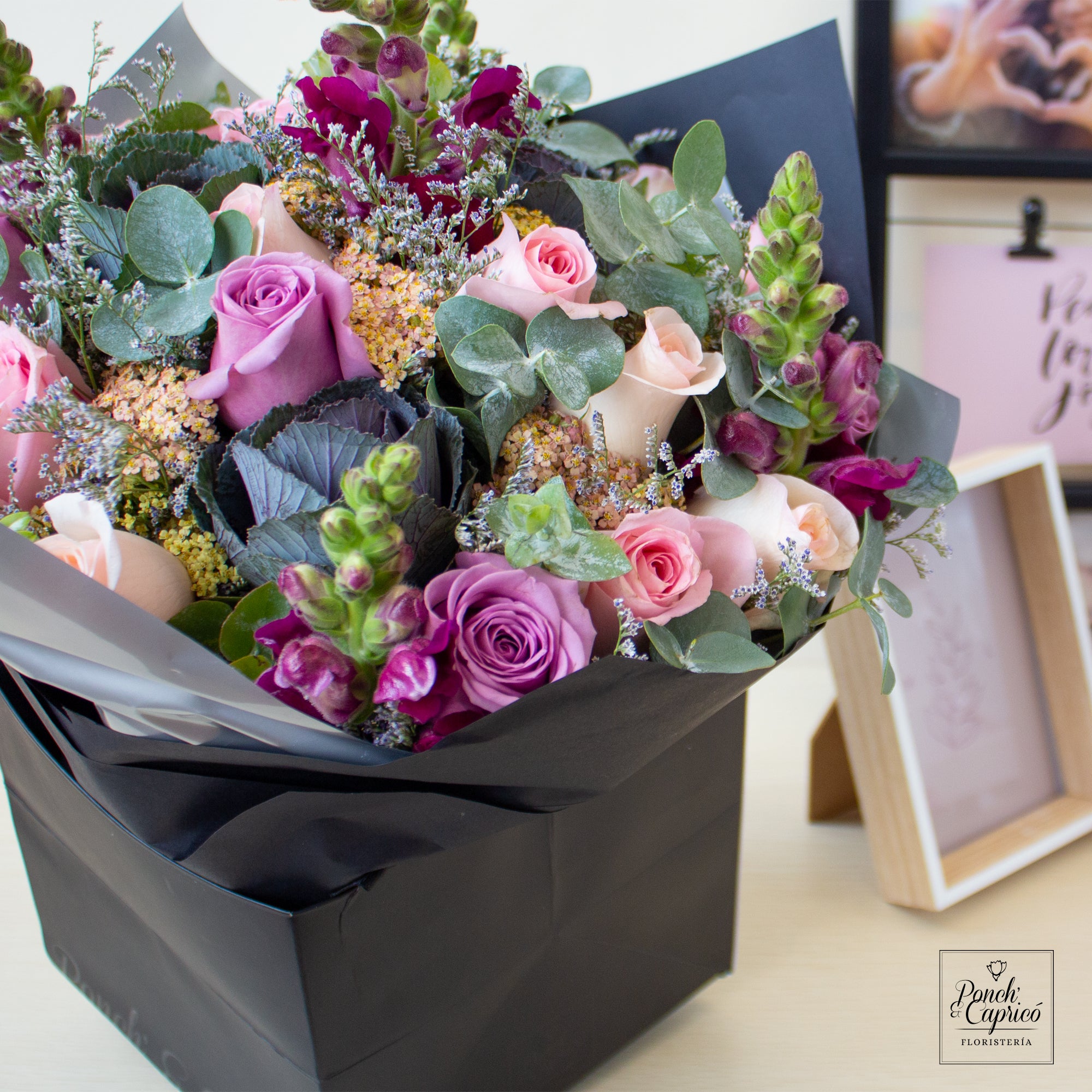 Bouquet Rosas lilas y rosadas con Eucalipto, Limonio, Aquilea y Lechuga con follajes de flores varias, atado a mano y envuelto en delicados y elegantes capas de papel. El arreglo incluye tarjeta personalizada, moño de tela y alimento para flores.